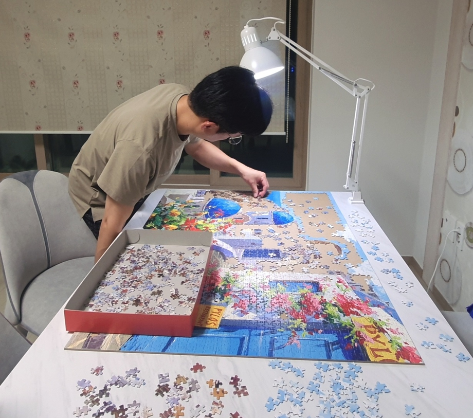 A picture of assembling a jigsaw puzzle with a lamp turned on at night