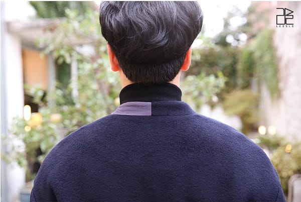 Back view of a male model wearing a navy-colored men's asymmetric oversized coat