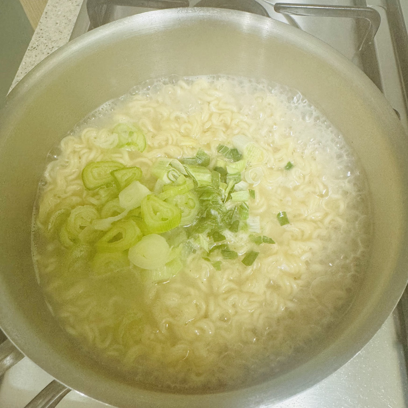 Una pentola con i noodles Sariguktangmyeon e la cipolla verde sopra