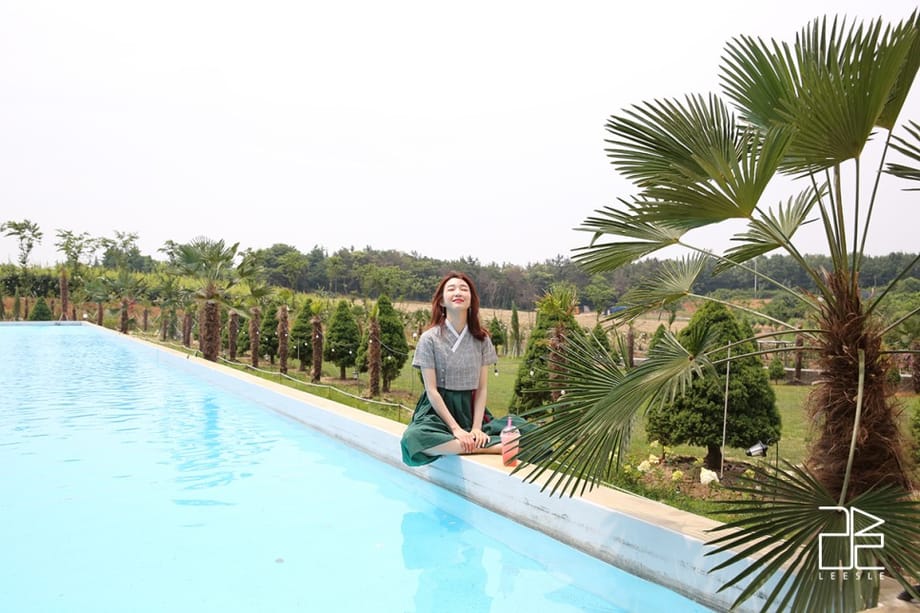 หญิงสาวสวมชุดฮันบกอยู่ริมสระว่ายน้ำ