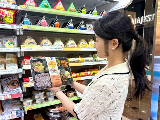 Een vrouw kijkt naar een Chuseok Bulgogi-stoofpot-lunchbox in een supermarkt.