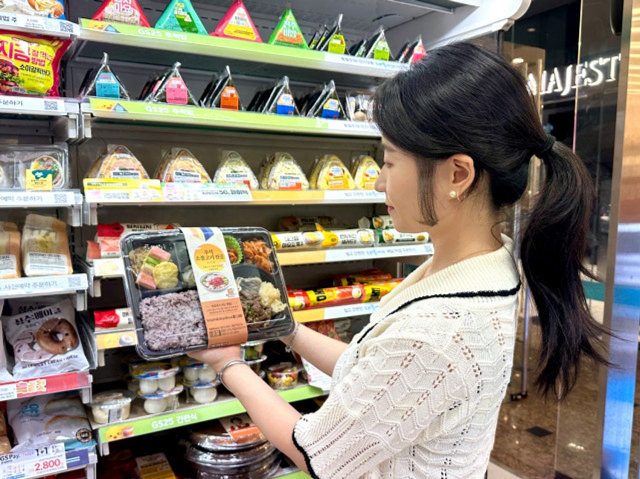 Eine Frau betrachtet in einem Convenience-Store eine Chuseok Bulgogi-Eintopf-Lunchbox